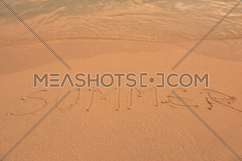 The Word Summer Written in the orange Sand background on a Beach at sunset