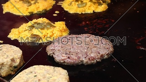 Close up of grilling beef burgers and cheddar cheese with jalapeno green peppers for hamburgers, high angle view