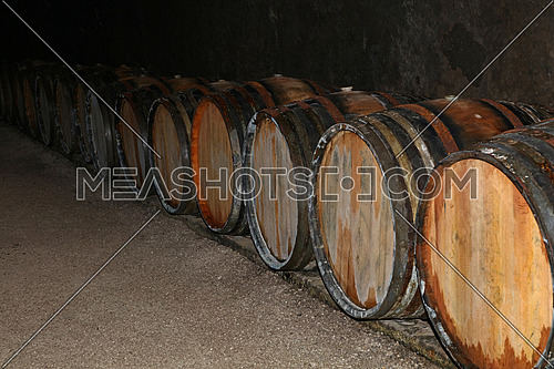 Close up rows of traditional aged natural oak wood wine barrels in winery cellar
