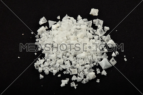 Handful of white Cyprian pyramid sea salt isolated on black paper background