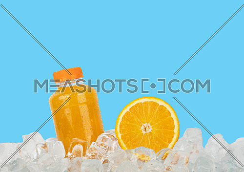 Close up one plastic PET bottle full of fresh orange juice and cut half orange slice on ice cubes isolated on blue background, low angle side view