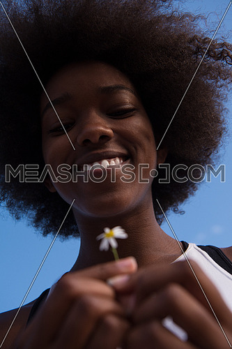 portrait of a young beautiful African American girl with a flower of daisy in her hand