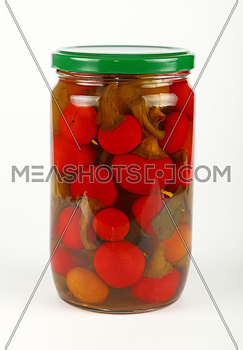 Close up of one glass jar of pickled small round red hot cherry chili peppers over white background, low angle view