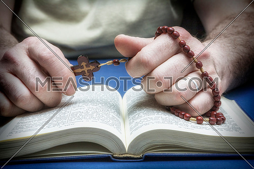 Christian believer praying to God with rosary in hand