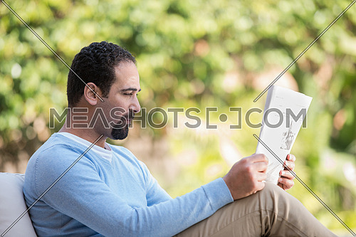young Middle Eastern man enjoying a coffee in the garden sunny summer morning