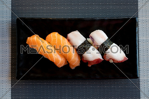 Traditional japanese nigiri sushi with salmon and sushi with octopus on black plate, view from above.