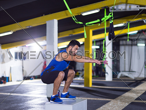 young athletic man training  jumping on fit box at crossfitness gym