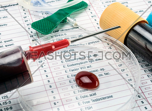 Blood sample on a petri disc along with syringe in a laboratory, conceptual image