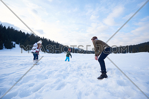 happy young  family playing in fresh snow  at beautiful sunny winter day outdoor in nature