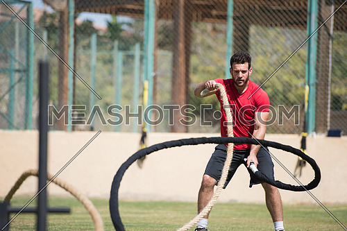 young middle eastern athletic man hard workout battle ropes outside on a sunny day