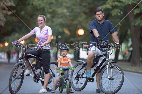 portrait of happy young family with bicycles in park at night
