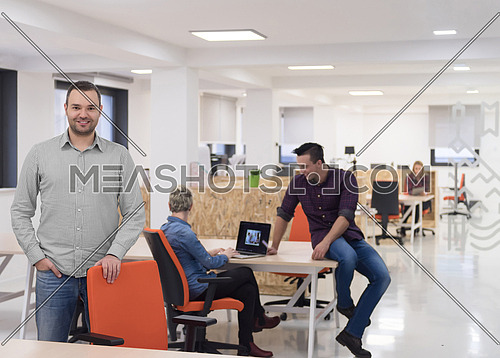 portrait of young businessman in casual clothes at modern  startup business office space,  team of people working together in background