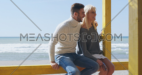 Happy couple enyojing time together on beach during autumn day