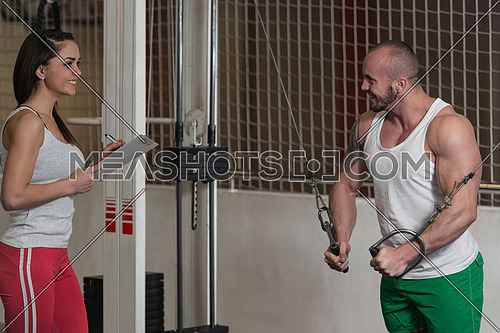 Personal Trainer Showing Young Man How To Train Chest Cable Crossover In The Gym