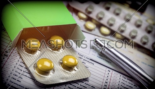 Blister pack of pills yellow and green box next to a form, conceptual image