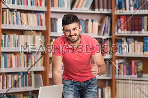 Portrait Of A Young Clever Student Showing Thumbs Up In College Library - Shallow Depth Of Field