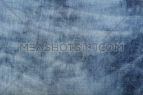 Dark indigo blue cotton jeans denim texture background with light washed distressed faded area, close up