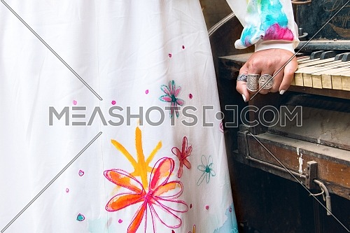 Closeup shot for Modern Dress and female hand wearing rings repose on vintage piano.