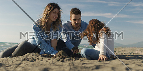 Family with kids resting and having fun at beach during autumn day
