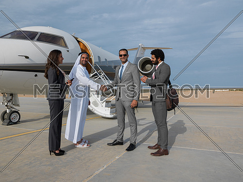 Young successful businessmen shake hands with their Arab business partner in front of the private airplane