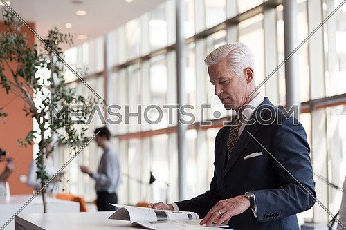senior business man reading magazine at modern bright office