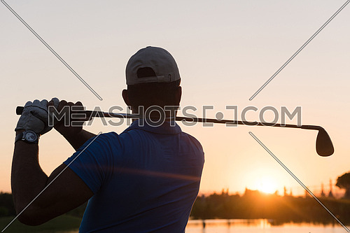 golfer hitting long shot with driver on course at beautiful sunset