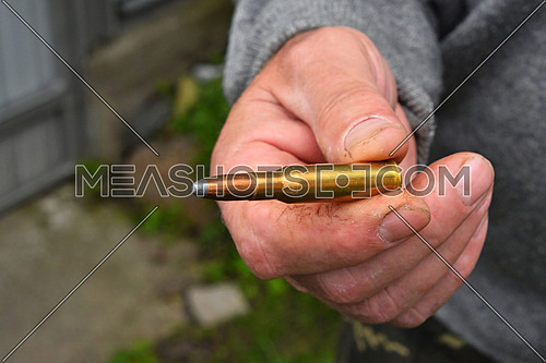 Old man hand holding and showing one 7.62 mm caliber ammunition bullet