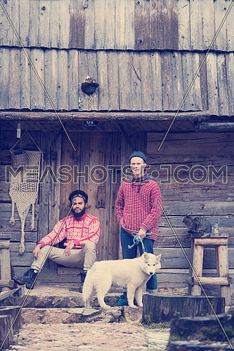hipsters couple portrait, two young  man with white husky dog  sitting in front of old wooden retro house