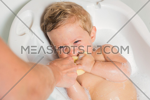 Wet baby playing with sponge