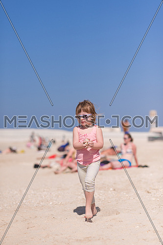 happy little girl at the seaside in the summer.Adorable little girl at beach during summer vacation. Happy baby with sunglasses by the sea or ocean
