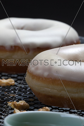 Side view of donuts with white glaze and nuts on a net