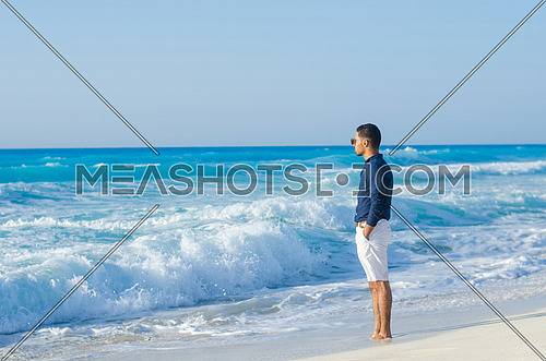 handsome man wearing a short and shirt by the sea