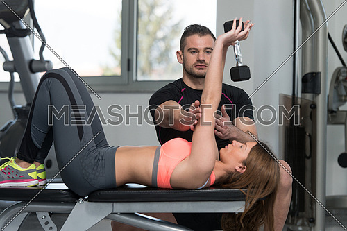 Personal Trainer Showing Young Woman How To Train Chest Exercise With Dumbbell In A Gym