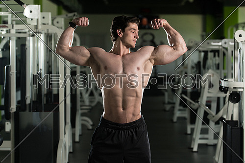 Portrait Of A Young Fit Man Showing Front Double Biceps Pose - Muscular Athletic Bodybuilder Fitness Model Posing