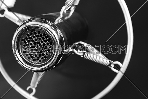 Vintage retro style old metal professional studio vocal voice and music recording microphone suspended with spiral round frame, close up, black and white