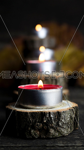 Christmas candles burning, decoration with wooden logs resting on rustic wooden background