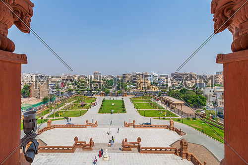 Cairo, Egypt- July 30 2020: View of garden of Baron Empain Palace with Heliopolis district in the far end framed by two decorated pillars at the roof of the palace