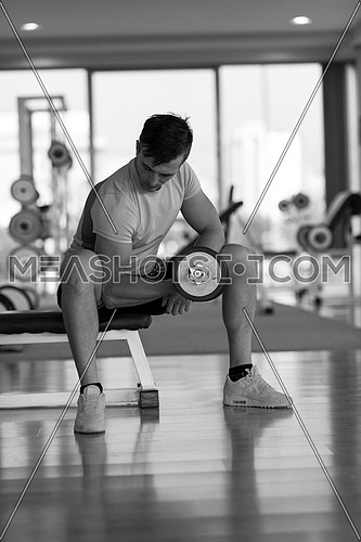 young handsome man working out with dumbbells in a fitness gym