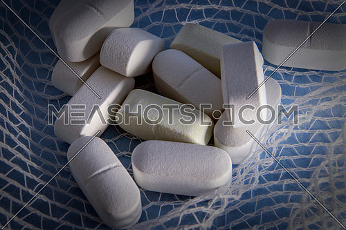 Some white pills wrapped in gauze on a blue background