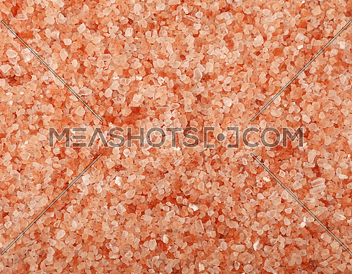 Close up background texture of medium crystals pink Himalayan salt, elevated top view, directly above