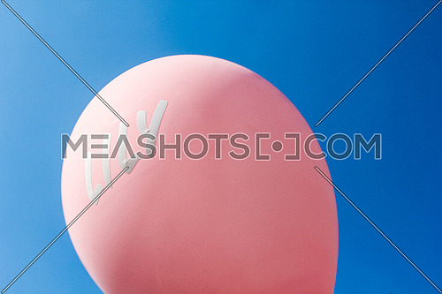 A pink balloon against blue sky