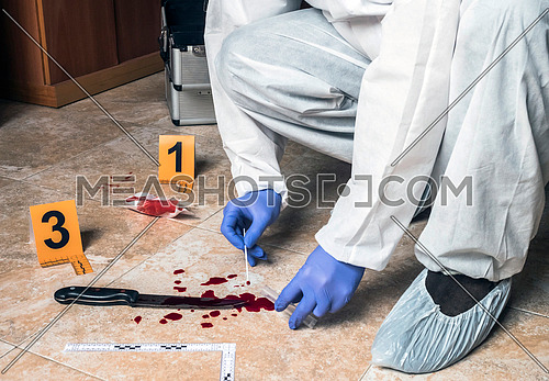 Expert Police takes blood sample from a blood knife at the scene of a crime, conceptual image
