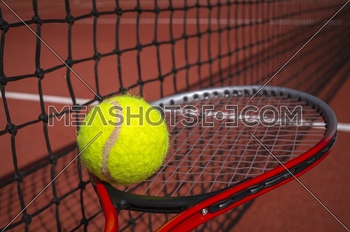 Tennis balancing ball on a racket alongside a net on a court in a sport and active healthy lifestyle concept