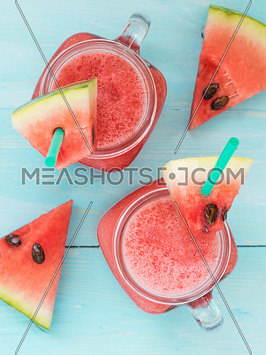 Watermelon smothie and slices on soft blue wooden background. Flat lay or top view. Vertical