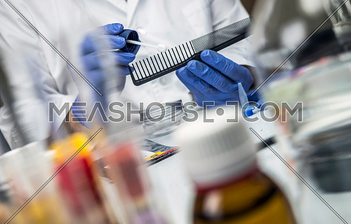 Scientist Police hold murder victim comb to find dna in crime lab, concept image