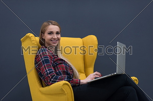 startup business, woman  working on laptop computer at modern office and sitting on creative yellow armchair