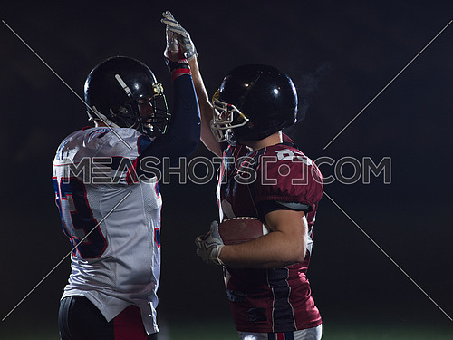 american football players giving high fives after scoring a touchdown on field at night