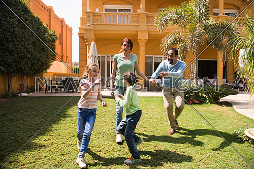 happy middle eastern young family enjoys a sunny day playing in the yard