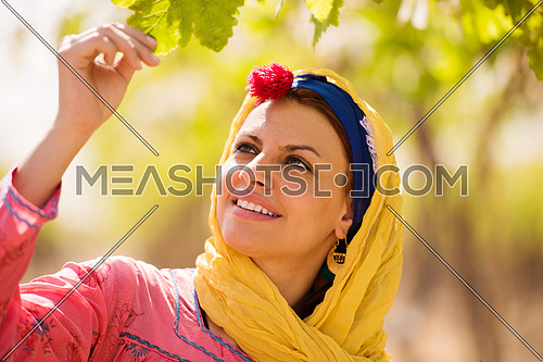 Young beautiful middle eastern woman enjoys the farm grapes with a smile on her face on a sunny summer day