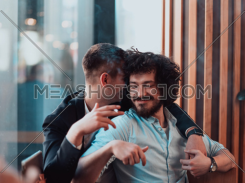 two lgbt guys sit romantically embracing in a modern cafe while smoking cigars